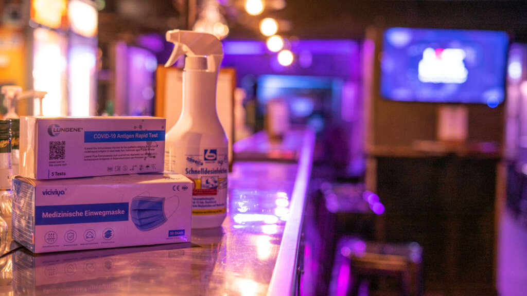 Hygienekonzept symbolisiert durch Desinfektionsmittel, Masken und Corona Tests auf der Theke der Lost Level Gaming Bar in Köln