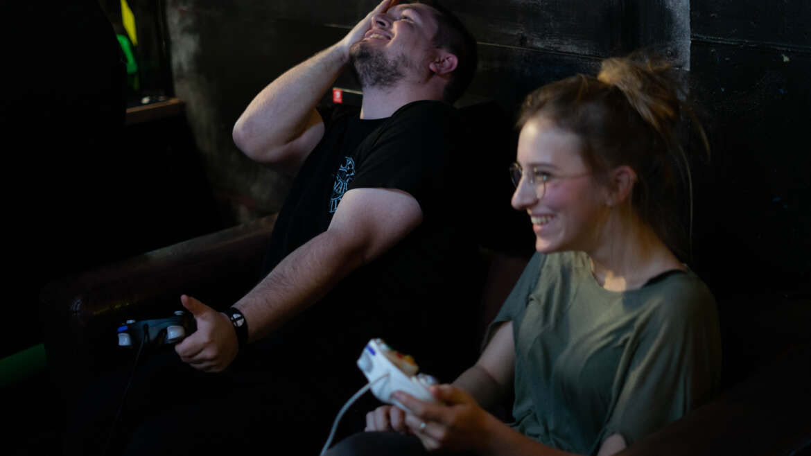 Eine Person lacht, eine weitere ärgert sich über eine gelungene Aktion in einem Smash Brothers Spiel.